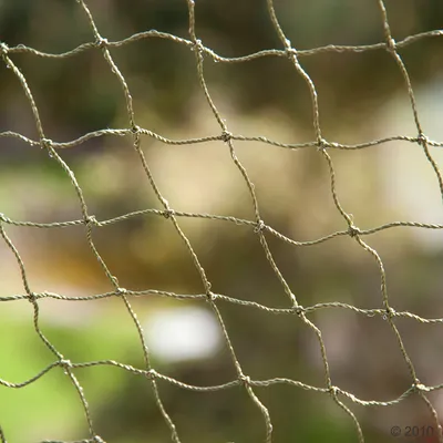 Gros plan sur un filet à mailles carrées en corde torsadée, couleur beige, sans marque ni texte visible.