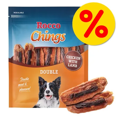 Rocco Chings Double koiranherkut, kanaa ja lammasta. Pakkaus ja kaksi herkkupalaa näkyvissä. Keltainen prosenttimerkki oikeassa yläkulmassa.
