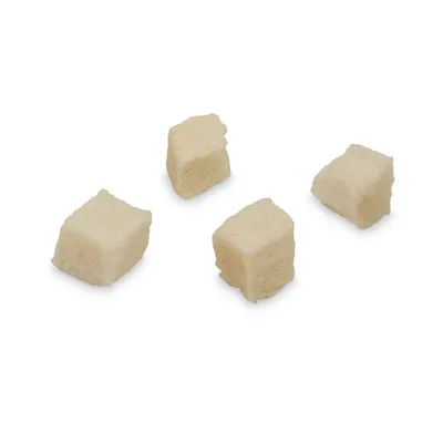 Quatre cubes de friandises claires, aspect lyophilisé, sans emballage ni marque visible, posés sur fond blanc.