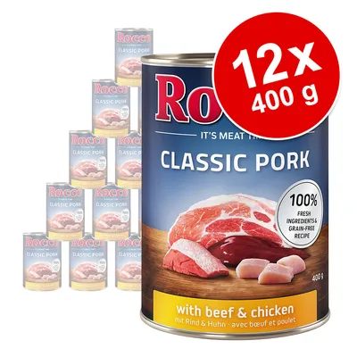 Lot de 12 boîtes Rocco Classic Pork 400 g, avec bœuf et poulet. Texte visible : 100 % fresh ingredients & grain-free recipe. Image des morceaux de viande sur l’emballage.