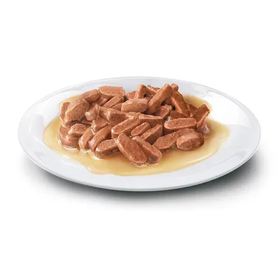 Närbild av köttbitar i sås på en vit tallrik, visad som exempel på våtfoder. Närbild av köttbitar i sås på en vit tallrik, visad som exempel på våtfoder.