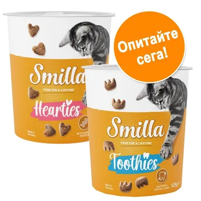 Две опаковки лакомства за котки Smilla: Hearties и Toothies, с изображение на котка и форма на гранули. Оранжев кръг с текст: Опитайте сега!