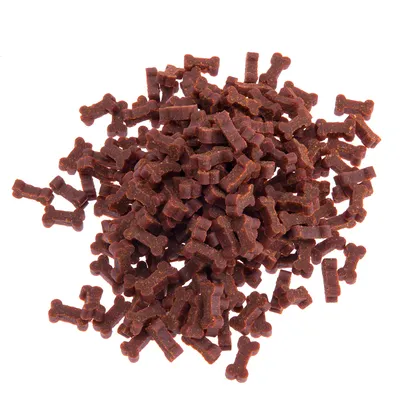 Friandises brunes en forme d’os, présentées en tas sur fond blanc. Aucun emballage ou marque visible.