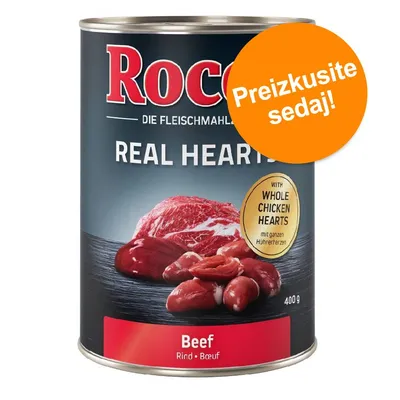 Konzerva Rocco Real Hearts Beef 400 g, z vidnim napisom 'WITH WHOLE CHICKEN HEARTS' in oznako 'Preizkusite sedaj!'. Na embalaži so slike mesa in piščančjih src.
