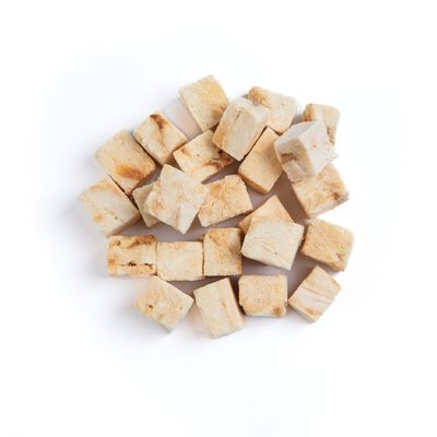 Several small, light brown, cube-shaped food treats arranged in a pile on a white background.