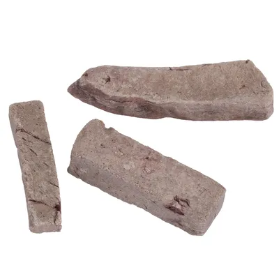 Tre brune, aflange stykker af et dyrefoder eller snack med ru overflade og ujævn form.