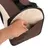 Main insérant un objet dans la poche extérieure d’un sac de transport pour animaux en tissu beige et marron, avec sangle noire visible.