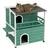 Grünes zweistöckiges Katzenhaus aus Holz mit Balkon und Dachterrasse, darauf eine braune Katze liegend.