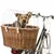 Cykelkorg av flätat trä med vitt metallgaller, fäst på cykel. Liten hund sitter i korgen under skyddsgallret.