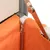 Nahaufnahme eines orangefarbenen Stoffbezugs mit Reissverschluss, befestigt an einer Holz- und Metallkonstruktion.