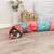 Toy tunnel in red and blue, suitable for small pets. Rabbit sitting in the tunnel on a wooden floor.