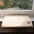 Beige windowsill mat made of soft fabric with embroidered brown paw print appliqué, placed on a radiator cover.