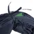 Detalle de tela azul oscuro con costuras y lazo, incluye un pequeño refuerzo verde visible. Material textil, sin logotipos ni texto identificativo.