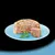 Chunky meat and jelly pet food served on a blue plate with a parsley garnish, showing texture and ingredients.