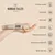 Nomad Tales München collar held in hand, beige fabric with gold metal parts. Visible text: Premium quality, Adjustable, Easy wear, Lightweight, Matching walking kit, Machine washable 30°, Made with love.