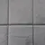 Šedá tkanina s měkkým, polstrovaným povrchem ve čtvercovém prošívání.