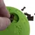 Grüner Spielball mit Pfotenmuster, befüllbar mit kleinen Knochenförmigen Leckerlis. Hand zeigt das Einfüllen der Leckerlis in die Öffnung des Balls.