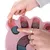 Interactive toy with pink paw shape. Hands place treats in compartments and move sliders with bone and fish symbols.