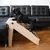 Hund benutzt beige Haustiertreppe, um auf ein schwarzes Ledersofa zu steigen. Treppe mit rutschfesten Stufen und stabiler Konstruktion.