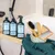 kooa Pflegeprodukte: Deep-Cleansing Shampoo, Sensitive Shampoo und Detangling Spray. Zubehör: Bürsten, Kamm und Handtuch mit kooa-Logo auf Bambusablage vor Badewanne.