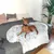 Hund liegt auf einer grauen Couch mit einem weissen, flauschigen Hundebett. Umgebung zeigt Kissen und eine Zimmerpflanze.