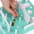 Hand places small brown treats on an interactive toy with white obstacles and a turquoise background.