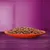 Close-up of a red plate with juicy pieces of meat in sauce, presented against a purple background.