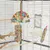 Vogelkäfig mit buntem Spielzeug aus Holz und Seil, Hirsekolbenhalter, Sitzstangen und Futterbehälter. Zubehör für Vogelbeschäftigung und Ernährung.