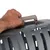 Hand greift den Griff einer grauen Transportbox mit Lüftungsschlitzen.