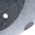 Gros plan sur une surface en feutre gris avec un bouton métallique et un trou rond visibles. Matériau : feutre, détail de fixation.