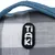 Tiaki-logotyp på ett gråvitt rutigt tyg med blått handtag.