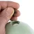 A hand fills brown treats into a green toy with an opening, suitable for keeping pets occupied.