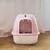 Затворена котешка тоалетна в розово с прозрачна врата и котка вътре. Марка Trixie видима отгоре.