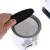 Hand placing a black filter onto a round sieve of a container. Close-up of assembly.