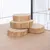 Quatre rondins de bois empilés, posés sur une surface en bois à l'intérieur d'une cage métallique.