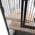 Bird cage with metal grid walls and wooden platform with round opening, suitable for birds to sit or play.