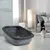 Bac à litière en plastique gris foncé avec rebord, posé au sol dans un salon moderne, chat noir et blanc visible à proximité.