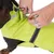 Manteau imperméable jaune fluo pour chien avec bande réfléchissante, attache de laisse visible sur le dos. Chien noir à poil court partiellement visible.