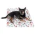 Cão deitado sobre uma manta branca com padrão colorido de cães e motivos de Natal.