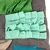 Product image of green and mint-coloured fleece material, cut into strips and shapes, on a grey background.