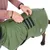 Manteau vert pour chien avec fermeture à scratch, personne ajustant la sangle sur le dos du chien. Trois bandes noires visibles et liseré réfléchissant sur le manteau.
