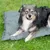 Graue Hundedecke auf grünem Gras, geeignet als Outdoor-Liegefläche.