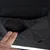 Nahaufnahme einer schwarzen Stofftasche mit elastischem Rand, in die eine Hand greift. Tasche ist Teil eines Produkts.