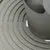 Primer plano de una superficie gris y texturizada con ranuras circulares y un elemento cilíndrico.