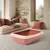 Arenero rosa para gatos con borde color crema, forma rectangular, presentado en una sala de estar con cojines beige y rojos en un banco.