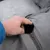 Hand opening zip of a grey cover, visible inner material underneath. Shows removable cover for cleaning or replacement.