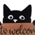 Fekete macska nagy szemekkel egy fa táblánál, amelyen az áll: 'Cats welcome'.
