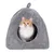 Grey, soft cat house with round entrance. A red and white cat is sitting inside and looking out. Grey, soft cat house with round entrance. A red and white cat is sitting inside and looking out.