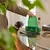 Earth Rated dog waste bags in green packaging, person taking out a bag. Accessories such as gloves and lead visible on table.