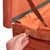 Nahaufnahme eines orangefarbenen Klettverschlusses an einem Holzrahmen, der von einer Hand geöffnet wird. Metallstreben und Stoffpolsterung sichtbar.